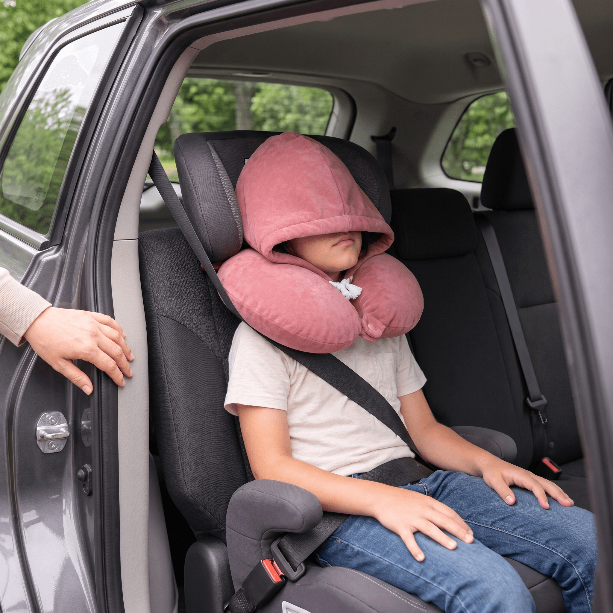 A child resting in a car seat wearing the Dusty Rose Snug Hood, with the hood over their eyes.